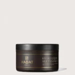 Dark brown Hadat cosmetics jar labeled Hydro Liquid Silk Treatment with black lid, gold branding on a light background, product for hair repair.