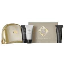 Gold metallic cosmetic pouch beside a skincare gift set—white and black tubes and a beige box with a triangular logo.