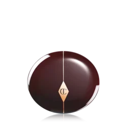 CHEEK-TO-CHIC-CLOSED-PACKSHOTpng - shopcosmoprof.com Glossy dark chocolate sphere with a gold diamond emblem at the center and a vertical seam, reflected on a surface.