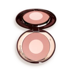 Open compact containing pink-toned face powder with a pale center, mirror reflecting above it