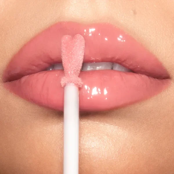 Close-up of glossy pink lips with a lip gloss wand applying product to the center of the lips