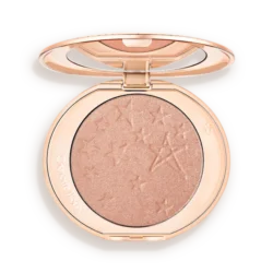Round rose-gold makeup compact opened to reveal a shimmery peach highlighter with star embossing on the powder surface.