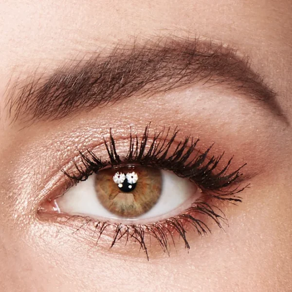 Close-up of a brown eye with shimmering peach/gold eyeshadow and long mascara-coated lashes.