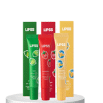 Three Lipss lip balm tubes in green lime, red strawberry, and yellow banana stand upright on a white pedestal.