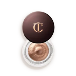 Bronze-cream eyeshadow in an open circular jar with a dark brown lid bearing a gold CT/CT logo, showing metallic product inside.
