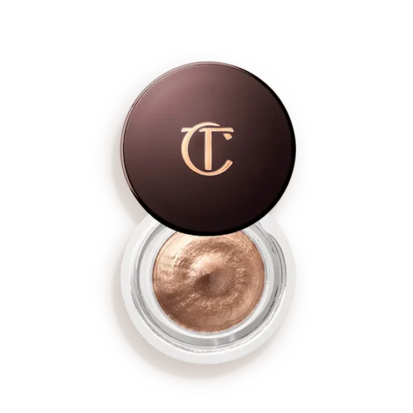Bronze-cream eyeshadow in an open circular jar with a dark brown lid bearing a gold CT/CT logo, showing metallic product inside.