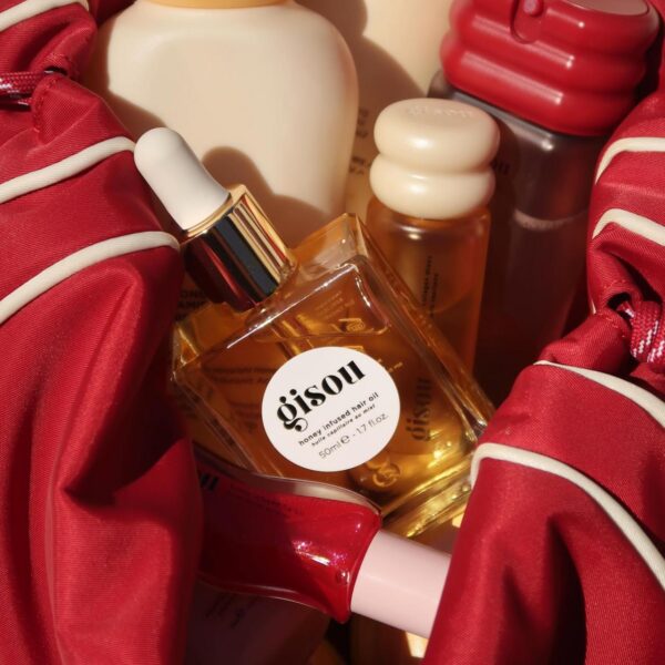 Cosmetic gifts inside a red satin bag: perfume bottle with white cap and a 'gisou' label in front, plus other small bottles and a red container.