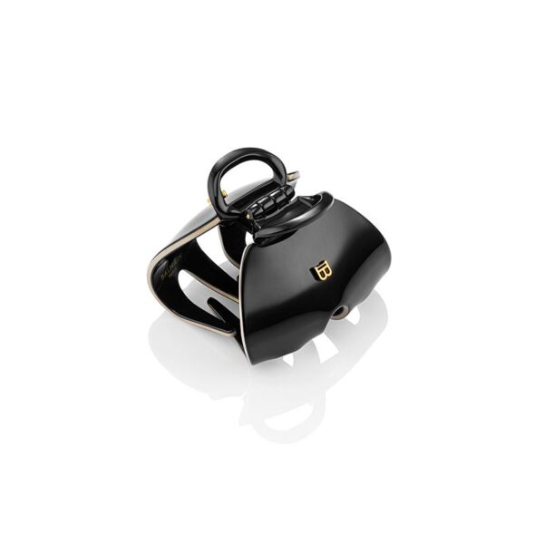 Black glossy, handbag-style accessory with a curved handle and gold JB logo on a white reflective surface.
