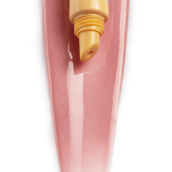 Close-up of a yellow banana lip balm tube with SPF 20 resting on a pink glittery nail surface.