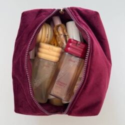Open magenta cosmetic bag filled with assorted travel-size bottles.