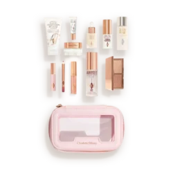 Charlotte Tilbury travel makeup kit opened to reveal mini skincare and cosmetics in a pink zippered case.