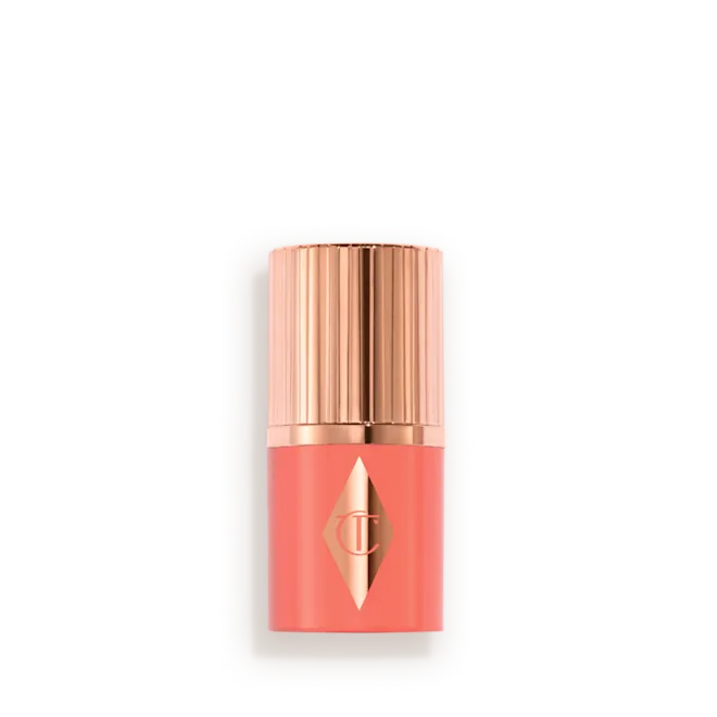 Lipstick in coral-pink shade with a rose-gold cap, displayed in a light, rounded display card (cosmetics product).