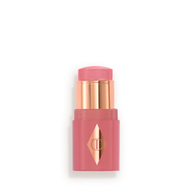 MINI_UNREAL_BLUSH_HEALTHY_GLOW_STICK_-_OPEN_-_ROSY_GLOWpng - shopcosmoprof.com Pink lipstick in a pink case with gold accents and a diamond-shaped logo on the front (cosmetic product).