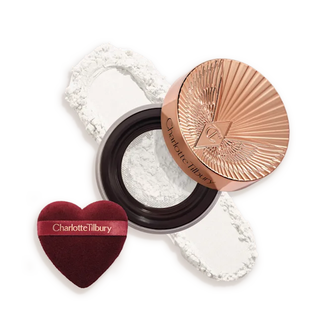 OPEN-PACKSHOT-TRANSLUCENT-SWATCH__1_png - shopcosmoprof.com Charlotte Tilbury compact with rose-gold lid, white pressed powder, and a burgundy heart-shaped puff beside it.