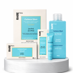 Set of RARE Paris skincare products in blue and white packaging on a white marble pedestal (Carbone Glacé line).