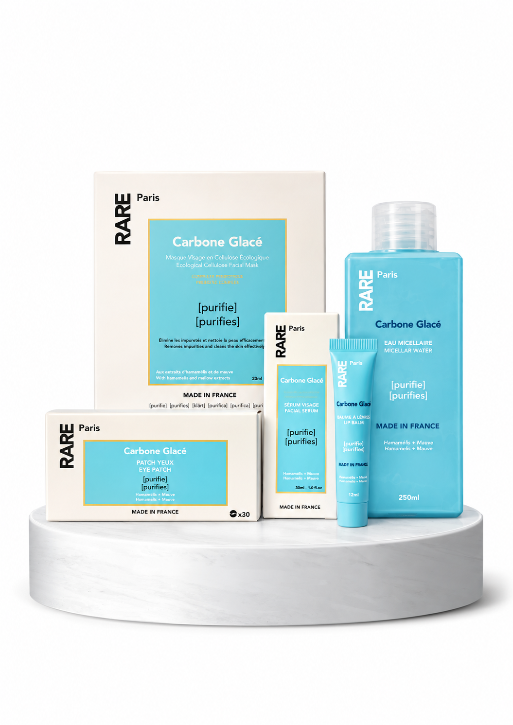 RARE PARIS CARBONE GLACÉ TYROS ODOS RITUALASpng - shopcosmoprof.com Set of RARE Paris skincare products in blue and white packaging on a white marble pedestal (Carbone Glacé line).