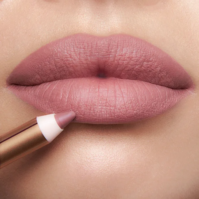 Close-up of lips being lined with a pink-nude lip pencil and matte pink lipstick.