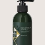 Dark green shampoo bottle with black pump on a beige background, labeled 'Detox Therapy Shampoo'