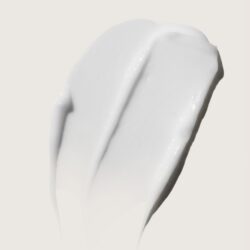 A dollop of glossy white cream or lotion smeared on a pale beige background