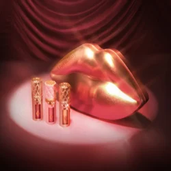 251027_Holiday-26_sl_SA_260604_Mini_Plumpgasm_Trio_R10_1000x1000jpg - shopcosmoprof.com Gold-toned lips sculpture with three pink Charlotte Tilbury lip products on a pink spotlight stage.
