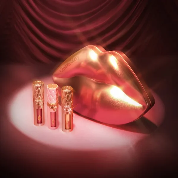 Gold-toned lips sculpture with three pink Charlotte Tilbury lip products on a pink spotlight stage.