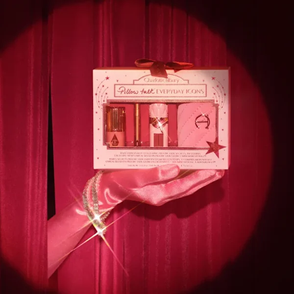 Hand in a pink satin glove holding a Pillow Talk Everyday Icons gift box against a pink velvet backdrop.