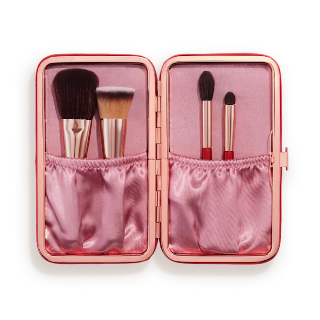 Open pink compact makeup case with brushes stored in two fabric pockets on each side, showcasing a kawaii-style kit.