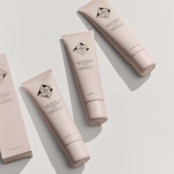 Pink hair primer tubes arranged on a pale background, product label reads 'Hair Discipline Style Primer 5‑In‑1' (HADAT). Scientific/cosmetic styling product promo image.